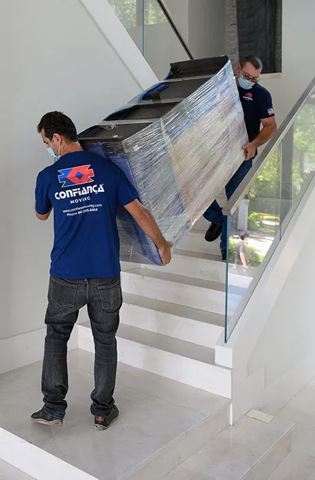 Confiança mover carrying a wrapped item down a staircase