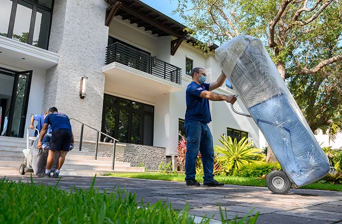 Confiança movers using a hand truck to move a wrapped mattress