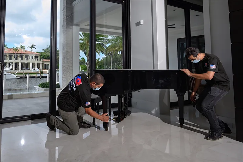 Confiança movers handling a grand piano in a waterfront home