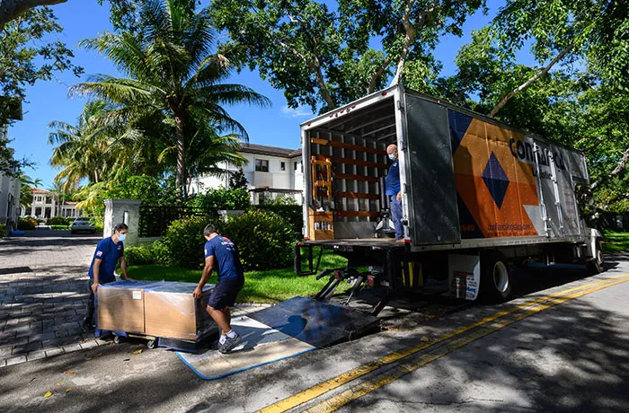Crew in Confiança shirts loading a crate onto the truck liftgate